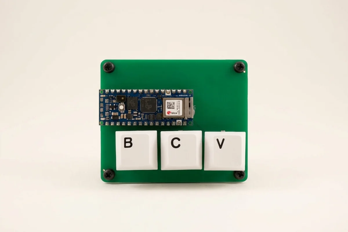 A green circuit board with an Arduino Nano RP2040 Connect and three white keycaps marked B, C and V